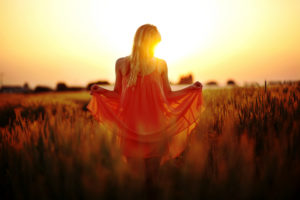 Woman with dress standing in the cornfield at sunset Woman with dress standing in the cornfield at sunset